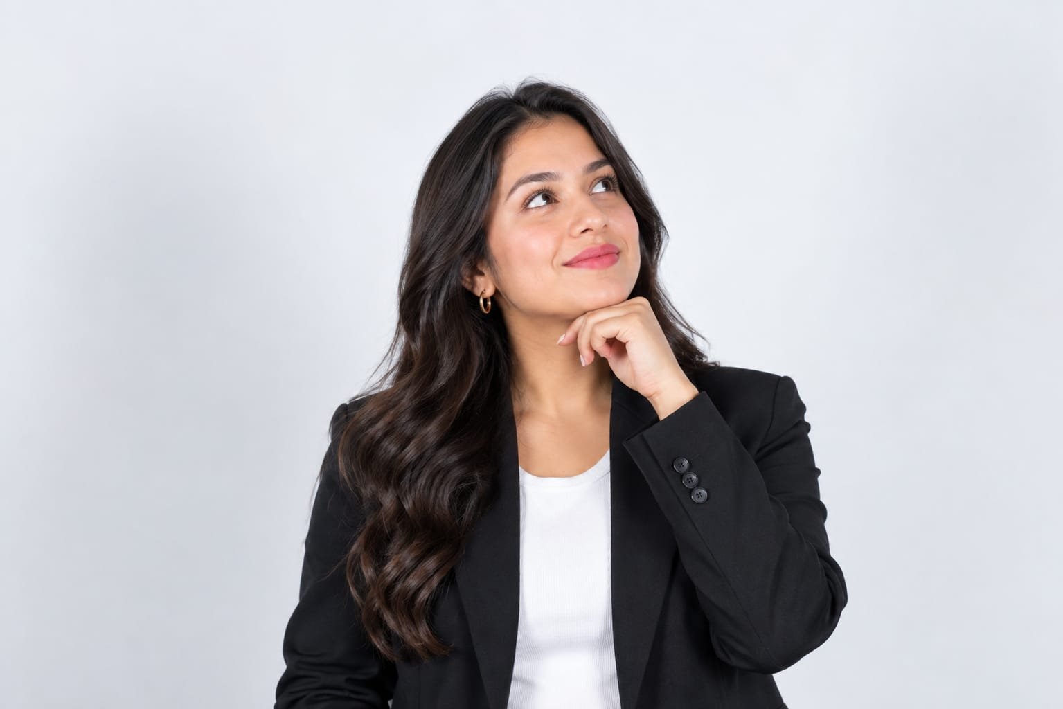 Professional female influencer wearing a black blazer, looking upward with a confident smile.